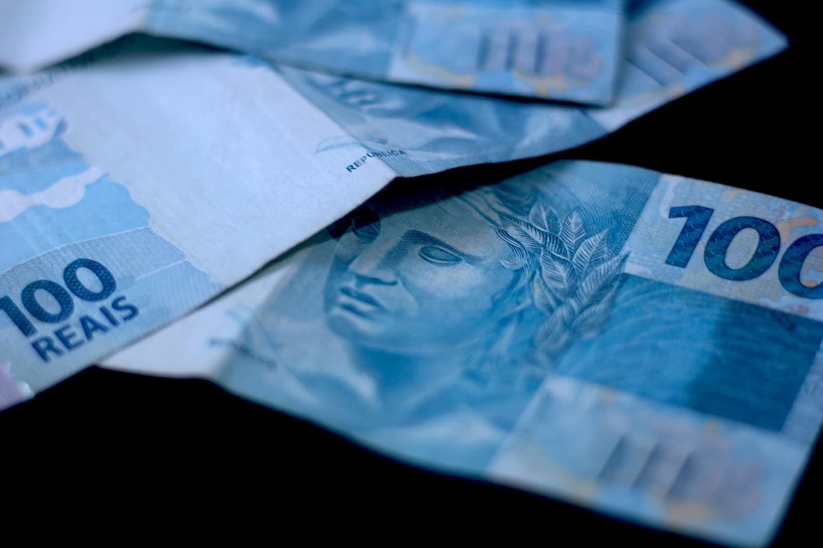 Notas de cem reais sobre fundo escuro